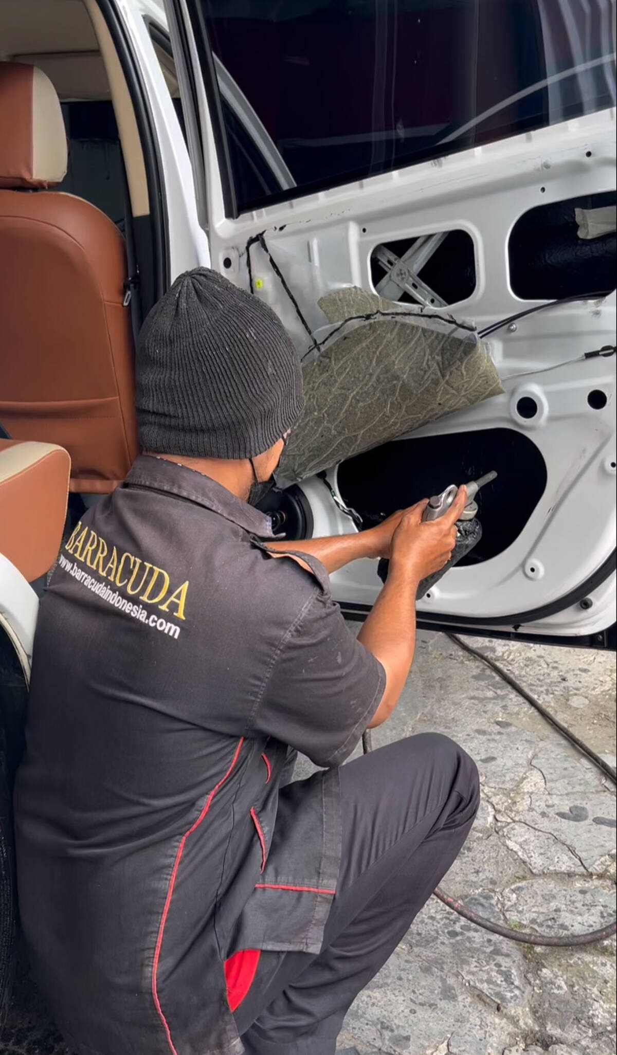 Proses instalasi peredam suara pada panel pintu mobil oleh teknisi Barracuda